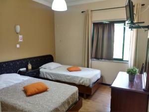 a hotel room with two beds and a television at Residencial Montanhês in Vila Real