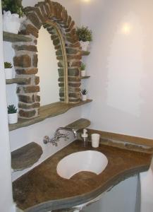 ein Badezimmer mit einem Waschbecken und einer Steinmauer in der Unterkunft Three Little Roses Country House in Mési
