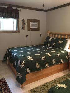 a bedroom with a bed with a green comforter at Warrensburg Inn & Suites - 6 Mi to Lake George in Warrensburg