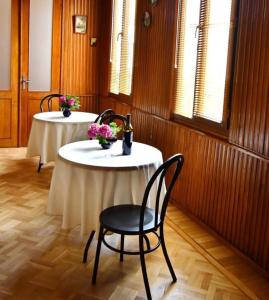two tables in a room with a chair and flowers at Hotel 1887 in Kutaisi