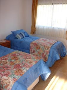 1 dormitorio con 2 camas con colchas azules y ventana en Turismo Vinapu en Hanga Roa