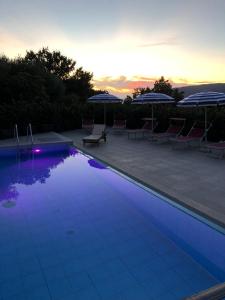 een zwembad met stoelen en parasols bij zonsondergang bij B&B Nonna Valentina in Centola