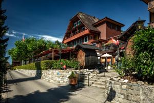 a large house with a stone wall in front of it at Seehotel Baumgarten in Kehrsiten