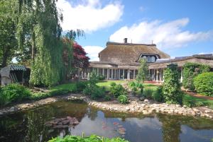a house with a pond in front of it at Ferienwohnung -Am Kanal- in Nordgeorgsfehn