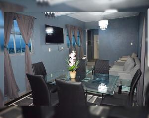 Hotel Milenio Nanacamilpa Tlaxcala في Nanacamilpa: غرفة معيشة مع طاولة وكراسي زجاجية
