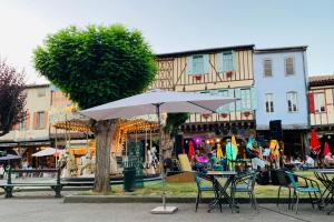 a table and chairs with an umbrella in front of a building at La Bienvenue in Tourtrol