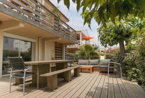 eine Holzterrasse mit einem Holztisch und Stühlen in der Unterkunft Le Chalet du Papa in Gruissan