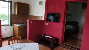 a room with a red wall with a table and a small table sidx sidx sidx at Apartments Carevi Dvori in Jezera