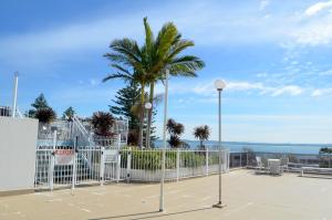 a white fence with a palm tree in the background at Nelson Towers Motel & Apartments in Nelson Bay