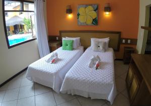 a bedroom with two beds with white sheets and green pillows at Anauí Pousada in Porto De Galinhas