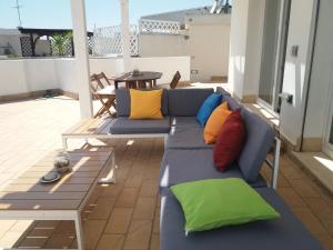 a blue couch with colorful pillows on a patio at Attico vista mare in Su Forti