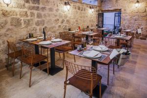 un restaurante con mesas y sillas de madera y una pared de piedra. en Boutique Room Kaliopi en Hvar