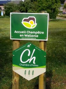 a green sign on two wooden posts in a field at Votre Horizon in Aywaille