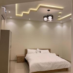 um quarto com uma grande cama branca e um lustre em Al Taif Villas em Taif