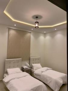 two twin beds in a bedroom with a light at Al Taif Villas in Ash Shuwaybiţ +33 photos