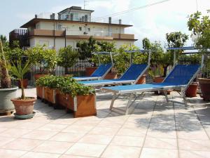 une rangée de chaises bleues assises sur une terrasse dans l'établissement Hotel Metron, à Cesenatico