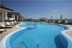 una piscina con sillas y el océano en el fondo en Coastal Dreams complex en Sveti Vlas
