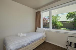 a bedroom with a bed and a large window at Cosy Central Affordable in Kaikoura