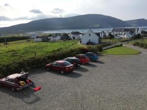 eine Reihe von Autos auf einem Parkplatz in der Unterkunft Roskeel House in Achill
