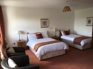una habitación de hotel con 2 camas y una silla en Roskeel House, en Achill