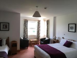 um quarto de hotel com uma cama e duas cadeiras e uma janela em Roskeel House em Achill