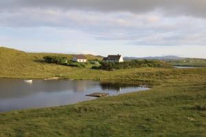 a house on a hill next to a body of water at Grey Goose Cottage in Lochs