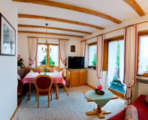 uma sala de estar com uma mesa, cadeiras e janelas em Haus Karoline em Reit im Winkl
