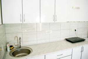 a kitchen counter with a sink and white cabinets at Apartments Leyla in Ulcinj +35 photos