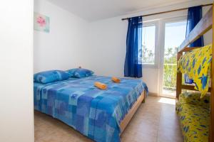 a bedroom with a bed with blue sheets and a window at Apartments Robinzon Petar in Gdinj