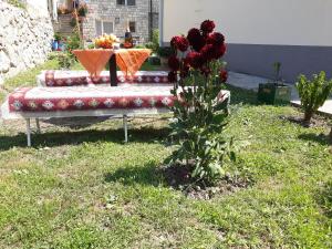 a bench with a table with flowers on it in a yard at Apartment Lotika in Višegrad