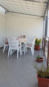 eine Terrasse mit weißen Tischen, Stühlen und Topfpflanzen in der Unterkunft Apartment Per - sea view & parking space in Banjol