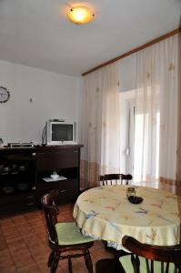 ein Esszimmer mit einem Tisch, Stühlen und einem TV in der Unterkunft Apartment Per - sea view & parking space in Banjol