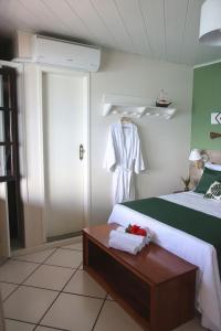 a bedroom with a bed and a table with a robe at Recanto do Sol in Praia de Araçatiba