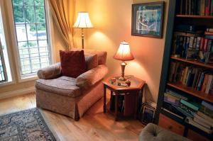 sala de estar con silla y mesa con lámpara en The Lace Curtain Cottage en Chadwicks