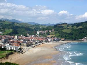 a view of a beach with buildings and the ocean at galerna aterpetxea in Zarautz