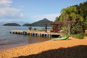 een strand met een huis en een boot op het water bij Recanto do Sol in Praia de Araçatiba
