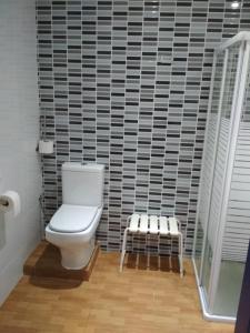 a bathroom with a toilet and a tile wall at galerna aterpetxea in Zarautz