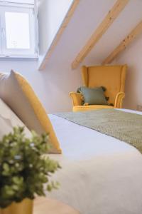 a attic bedroom with a bed and a chair at Living Coimbra Corpo de Deus in Coimbra