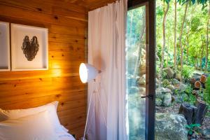 a bedroom with a bed and a glass door with a window at Caparica Azores Ecolodge in Biscoitos