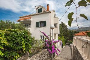 una casa blanca con una valla y flores púrpuras en Agape Duplex Apartment, en Dubrovnik