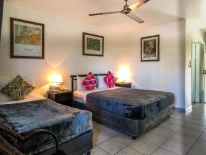South Cairns Resort في كيرنز: غرفة نوم بسريرين عليها وسائد وردية