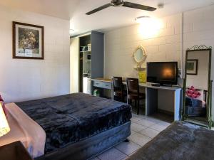 South Cairns Resort في كيرنز: غرفة نوم بسرير ومكتب مع تلفزيون