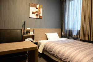 Ueda Ekimae Royal Hotel في أويدا: غرفة في الفندق مع سرير ومكتب
