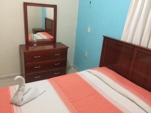 a bedroom with a bed with a dresser and a mirror at Hotel De Santiago in Chiapa de Corzo