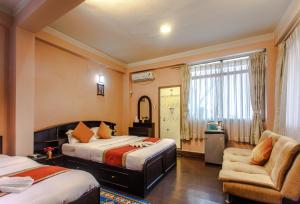 una habitación de hotel con 2 camas y una silla en Hotel Nepalaya, en Katmandú