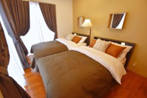 two beds in a hotel room with a window at Guest House Tsukishiro in Nanjo