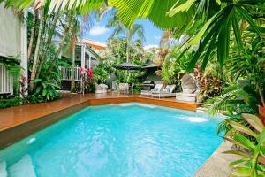 - une piscine dans une cour avec des palmiers dans l'établissement Mantra on the Inlet, à Port Douglas