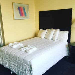 um quarto com uma cama grande e almofadas brancas em Sandy Shores Resort em North Wildwood