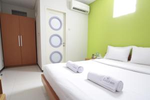 2 camas en una habitación con paredes verdes en LeGreen Suite Tebet, en Yakarta