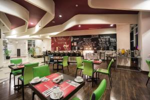 ジャカルタにあるファーヴェホテル プルイットジャンクショ​​ンの緑の椅子とテーブル、カウンターのあるレストラン